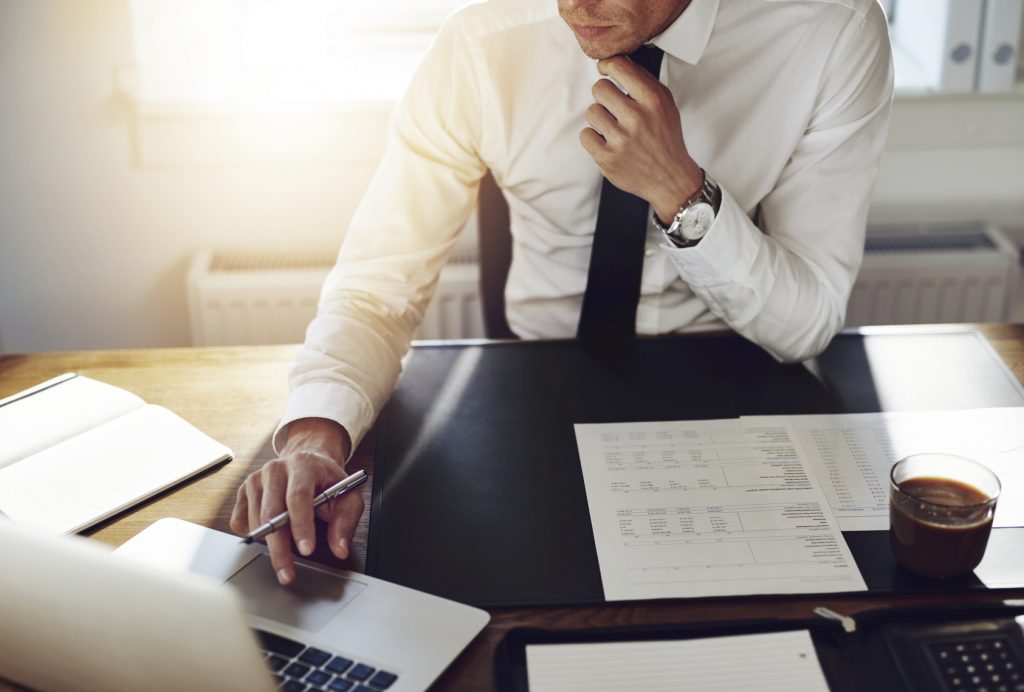 Homme au bureau devant un ordinateur et travaillant sur ses dossiers